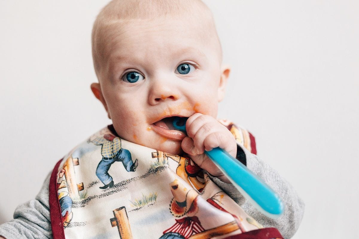 https://www.kindercare.com/-/media/contenthub/images/article-images/lets-eat/baby-foods/to-have-and-to-hold-10-fab-ways-to-store-and-serve-baby-food_messy-baby-spoon-in-mouth.jpg